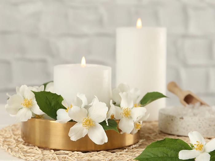 two white candles burning and white flowers